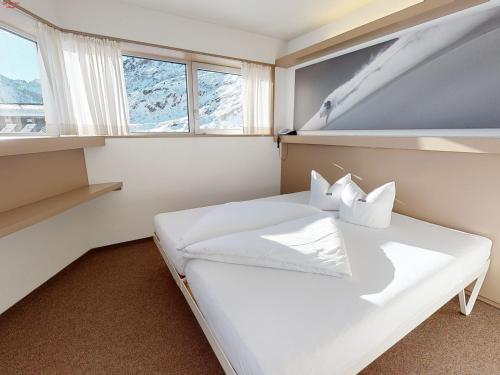 a bedroom with a large white bed and windows at Hotel Ski Austria St.Christoph a.A. in Sankt Christoph am Arlberg