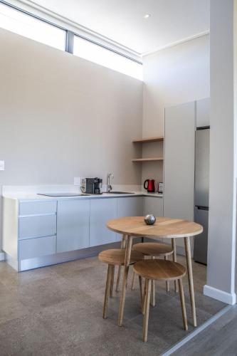 a kitchen with a wooden table and two stools at Hilltop Bayview Luxury Apartments in Plettenberg Bay
