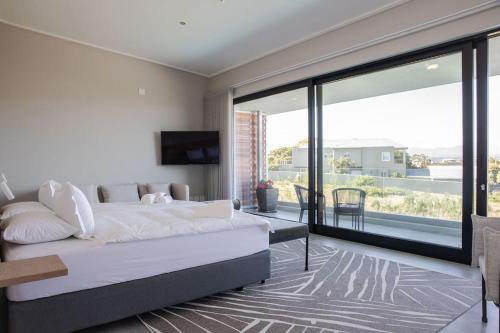 a bedroom with a large bed and a large window at Hilltop Bayview Luxury Apartments in Plettenberg Bay