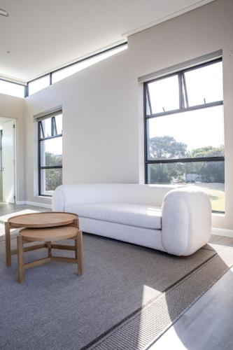 a white bedroom with a large bed and a coffee table at Hilltop Bayview Luxury Apartments in Plettenberg Bay