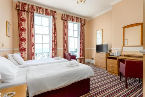 a hotel room with two beds and a television at Russell Hotel in Weymouth
