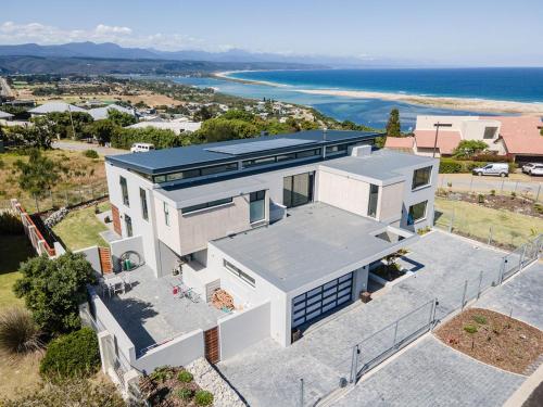 an aerial view of a white house with the ocean at Hilltop Bayview Luxury Apartments in Plettenberg Bay