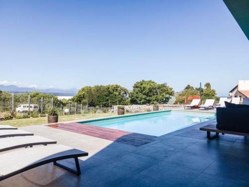 a large swimming pool with lounge chairs next to it at Hilltop Bayview Luxury Apartments in Plettenberg Bay