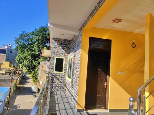 a yellow house with a door on a street at Anandam Home Stay in Rishīkesh