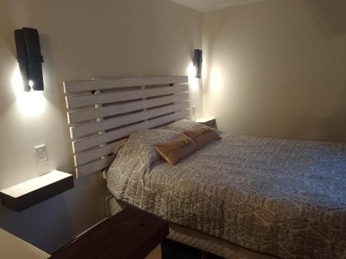 1 dormitorio con 1 cama y 2 luces en la pared en VILLA DE MONTAÑA LOS CHACAYES, Manzano Histórico, Tunuyán en Tunuyán