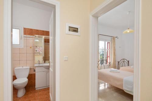 a white bathroom with a toilet and a sink at Villa Kalithea in Nisaki