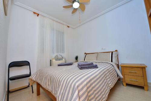 a bedroom with a bed and a chair and a ceiling fan at CamposolBungalow 3bedroom Bbq Ac Tv Wifi in Mazarrón