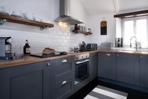 uma cozinha com armários azuis e um lavatório em The Lambing Shed, Cornwall em Altarnun