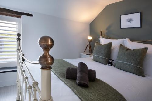 sypialnia z białym łóżkiem z zielonymi poduszkami w obiekcie The Lambing Shed, Cornwall w mieście Altarnun