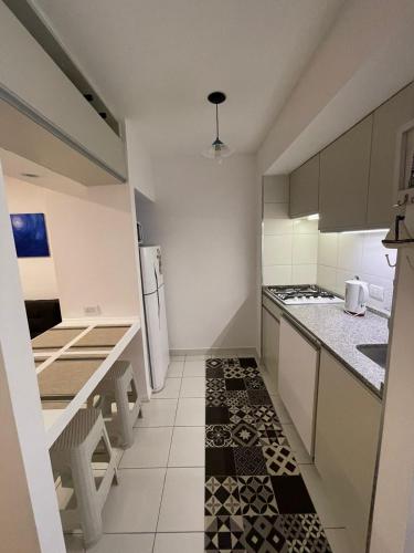 eine kleine Küche mit weißen Schränken und einem schwarz-weißen Boden in der Unterkunft Monoambiente Evans in Ciudad Lujan de Cuyo