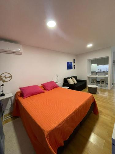 1 dormitorio con 1 cama grande de color naranja y 1 sofá en Monoambiente Evans en Luján de Cuyo