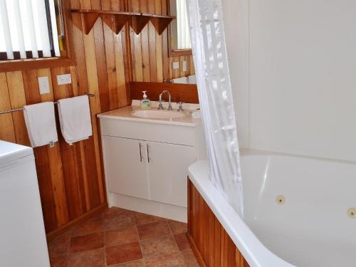 a bathroom with a sink and a tub and a toilet at Freycinet Sands in Coles Bay