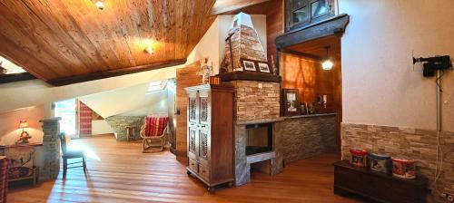 a living room with a stone fireplace and a wooden floor at Hostdomus - Weekend apartments in Pragelato