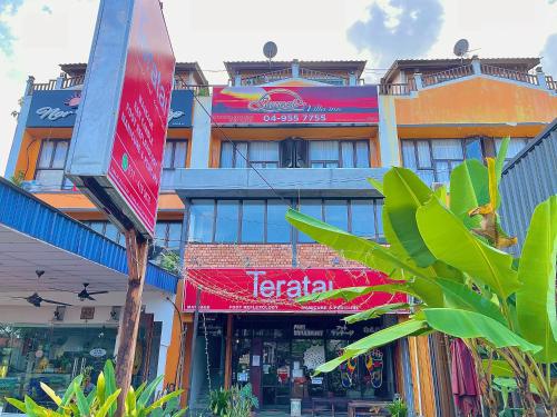 a building with a sign in front of a store at Arch Dormitorio Cenang in Pantai Cenang