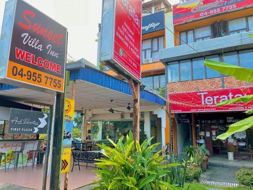 a group of shops with signs in front of a building at Arch Dormitorio Cenang in Pantai Cenang