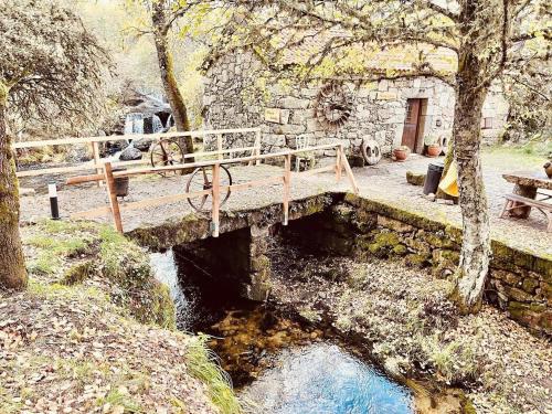 a wooden bridge over a river with a picnic table at Moinho de Brião in Montalegre