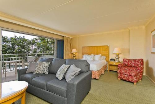 um quarto de hotel com um sofá e uma cama em Ilikai Apt 308 - Spacious Studio with Stunning Ocean & Harbor Views em Honolulu