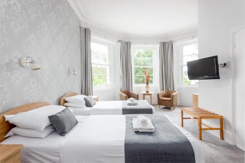 a hotel room with two beds and a tv at Devonshire Hotel in Torquay