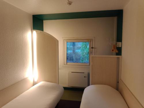 een kamer met een spiegel, een bed en een raam bij chicÔtel Périgueux Boulazac in Boulazac