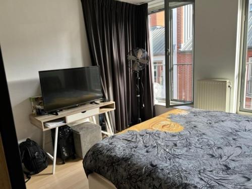 a bedroom with a bed and a flat screen tv at center City appartement in Alphen aan den Rijn