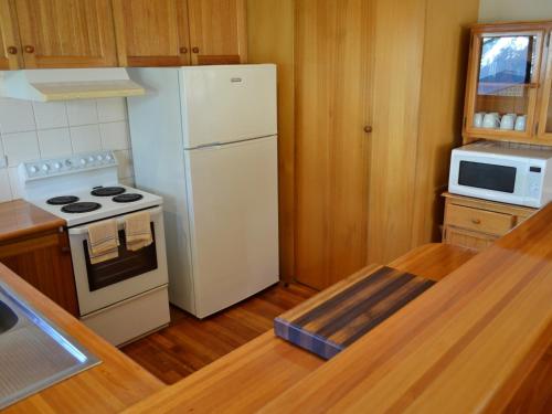 a kitchen with a white refrigerator and a stove at Freycinet Sands in Coles Bay