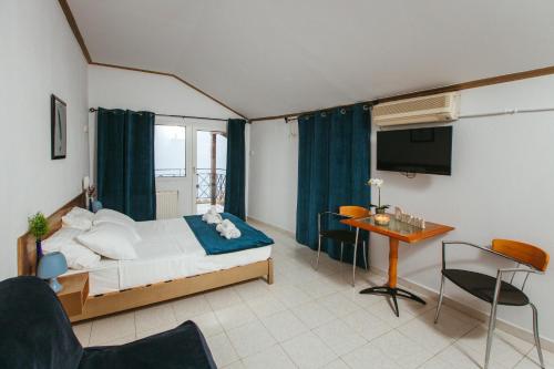 Schlafzimmer mit einem Bett, einem Schreibtisch und einem TV in der Unterkunft Hotel Christina - Happy Days in Karítsa
