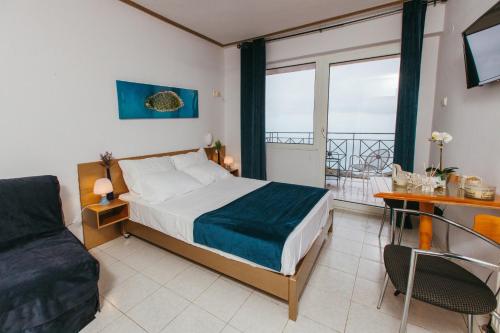 ein Schlafzimmer mit einem Bett, einem Sofa und einem Fenster in der Unterkunft Hotel Christina - Happy Days in Karítsa