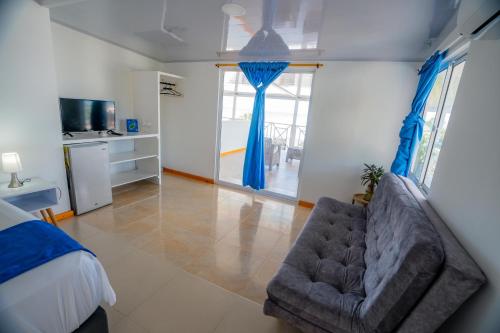 a bedroom with a couch and a bed with blue curtains at Hotel El Pirata Morgan in Providencia