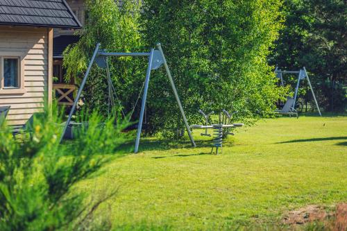 a park with two swings and a playground at SeaUSasino - Luksusowe Drewniane Domy z Kominkami in Sasino