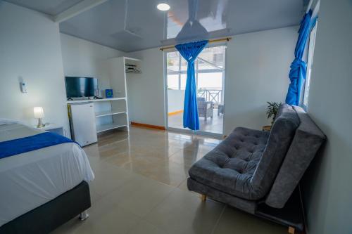 a bedroom with a bed and a chair with blue curtains at Hotel El Pirata Morgan in Providencia