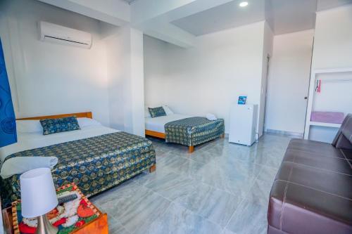 a hotel room with two beds and a couch at Hotel El Pirata Morgan in Providencia