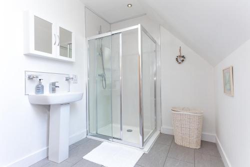 a white bathroom with a shower and a sink at 1 Eden at Williamscraig Holiday Cottages in Linlithgow