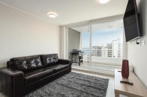 un sofá de cuero negro en una sala de estar con una gran ventana en departamento 9 norte 450, en Viña del Mar