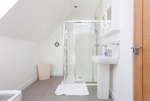 a white bathroom with a shower and a sink at 2 Eden at Williamscraig Holiday Cottages in Linlithgow