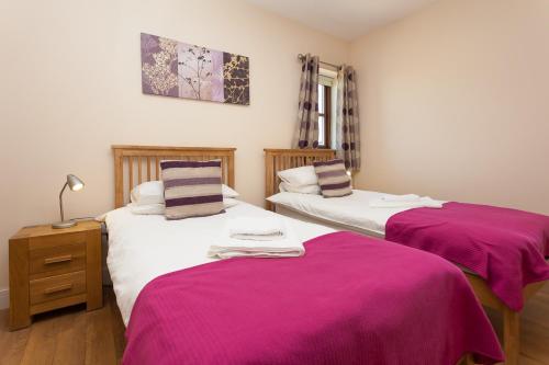 2 camas en una habitación con sábanas rosas. en 2 Eden at Williamscraig Holiday Cottages en Linlithgow