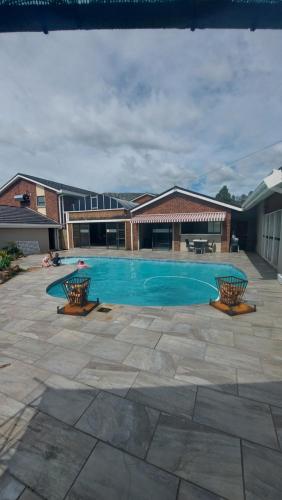 una piscina con 2 sillas en un patio en Skylight Guest House, en Harrismith