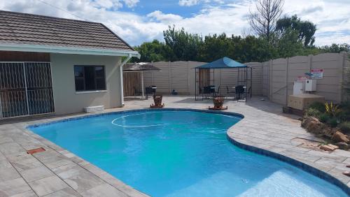 a swimming pool in a yard with a patio at Skylight Guest House in Harrismith