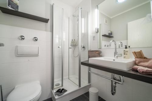 a white bathroom with a sink and a shower at Auszeit Hotel Hamburg in Hamburg