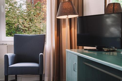 a living room with a tv and a chair and a lamp at Auszeit Hotel Hamburg in Hamburg