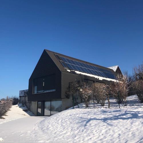 una casa con paneles solares en la nieve en LOGIS125 I Barbara Hofmann, en Gamlitz