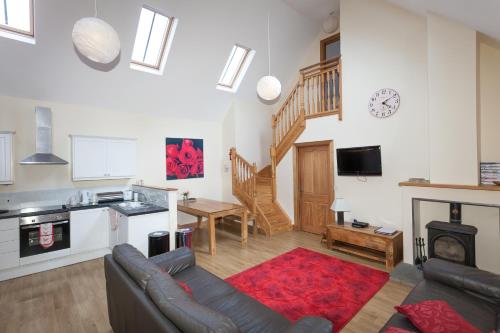 a living room with a couch and a kitchen at Honeysuckle Cottage at Williamscraig Holiday Cottages in Linlithgow