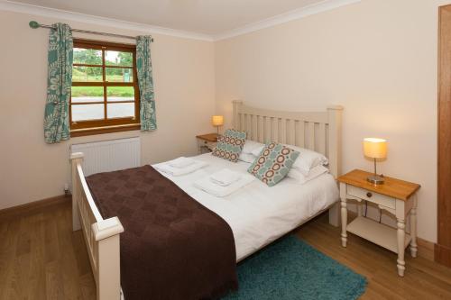 a bedroom with a large bed and a window at Honeysuckle Cottage at Williamscraig Holiday Cottages in Linlithgow