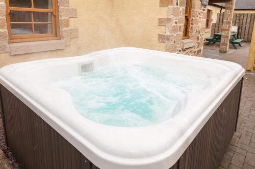 a large bath tub with blue water in it at Honeysuckle Cottage at Williamscraig Holiday Cottages in Linlithgow