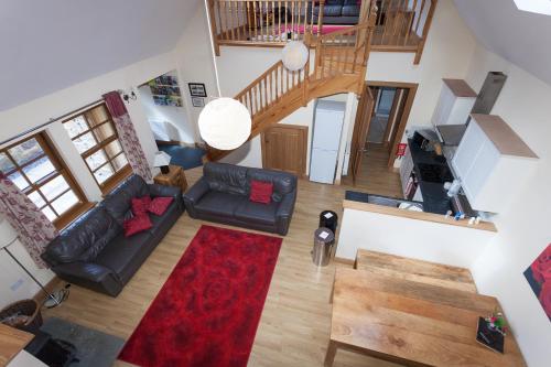 a living room with a couch and a red rug at Honeysuckle Cottage at Williamscraig Holiday Cottages in Linlithgow