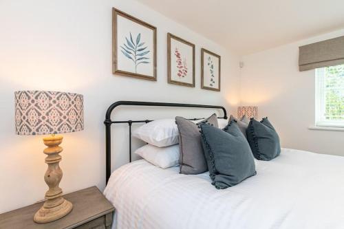 a bedroom with a bed with pillows and a lamp at Oxfordshire Living - The Sunderland Apartment - Bladon in Bladon