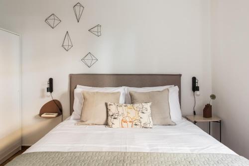 een slaapkamer met een bed met witte lakens en kussens bij Groovy 2BR Apartment in Koukaki by UPSTREET in Athene