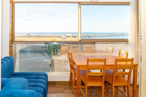 a dining room with a table and chairs and a large window at PUERTO MARINA ASILAH in Asilah