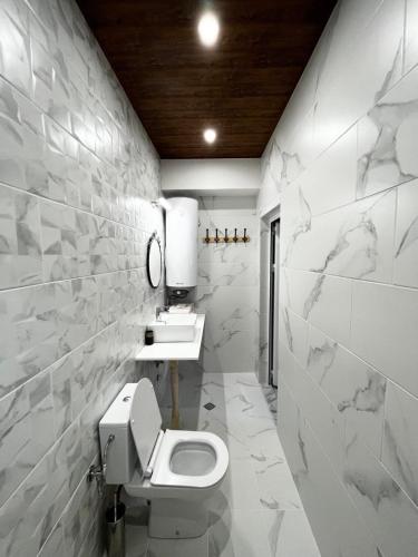a white bathroom with a toilet and a sink at Roots Apartment 2 in Borovets