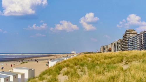 una spiaggia con persone che camminano sulla sabbia e sugli edifici di Dolce Vita - zonnig familie appartement met garagebox a Nieuwpoort