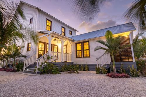 a white house with a palm tree in front of it at Casa Blanca and The PoolClub at Mahogany Bay in San Pedro